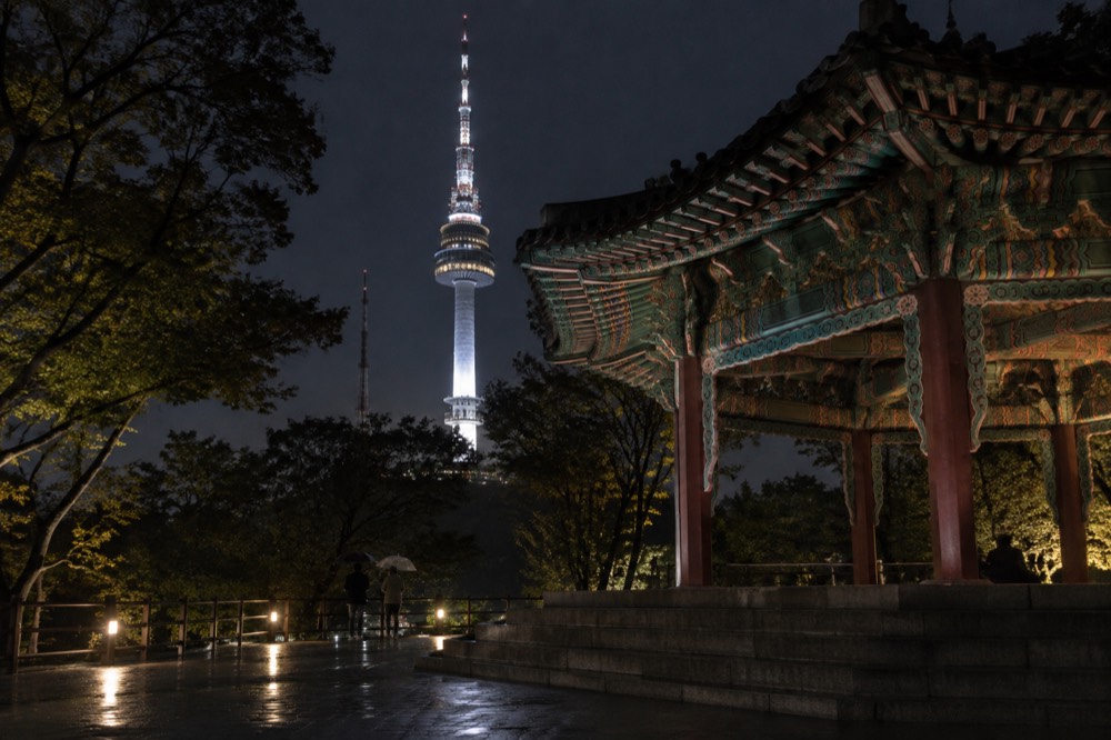 The illuminated tower at night seen from the summit plaza below