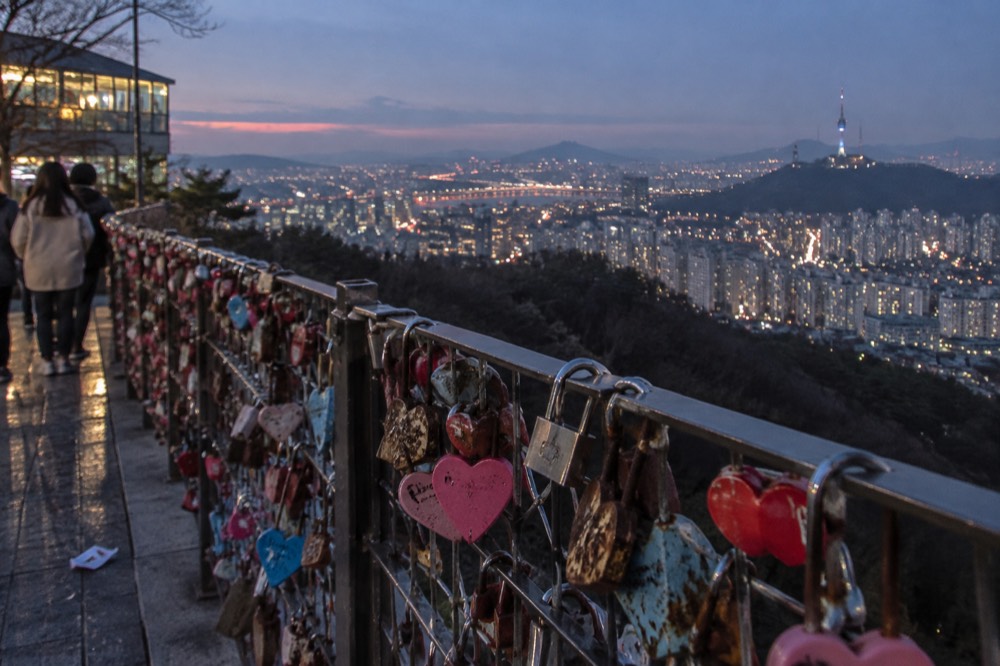 A couple's padlock clipped to a fence on a hilltop terrace at dusk