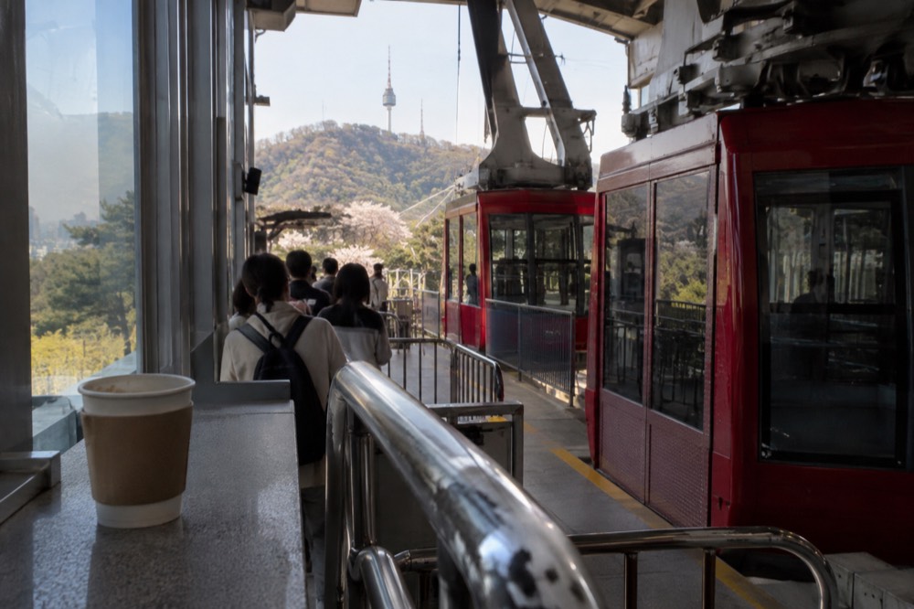 Cable car station platform with red cabins and passengers boarding at the Namsan base station