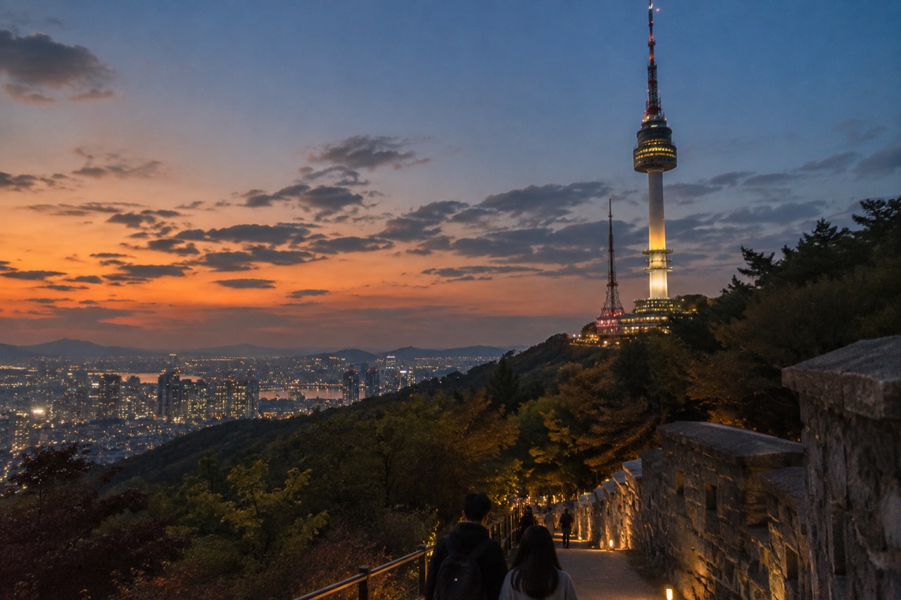 N Seoul Tower lit up at dusk with Seoul city lights spreading behind it
