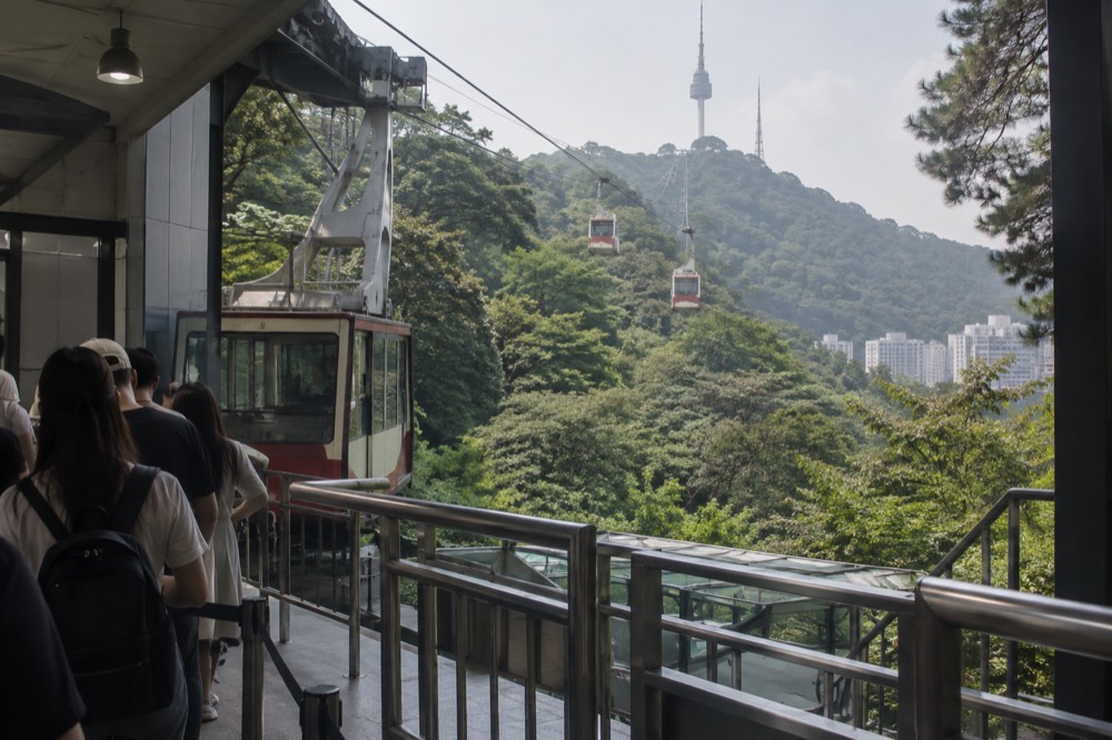 Cable car cabins travelling up the forested slope toward N Seoul Tower