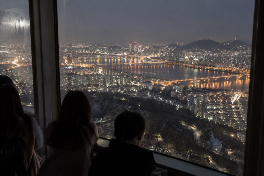 Night view from an observation window showing a river winding through a lit city