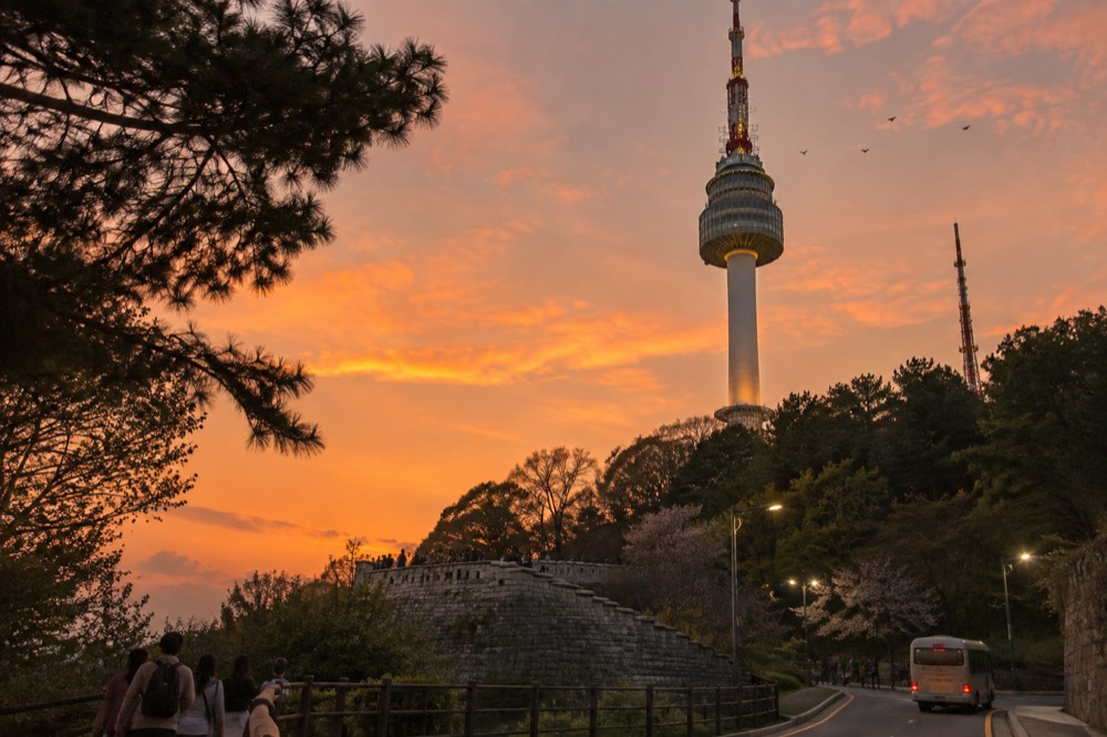 The upper mast and body of N Seoul Tower against an evening sky