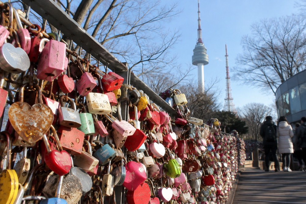 Hundreds of coloured padlocks attached to railings and fences at a hilltop viewpoint