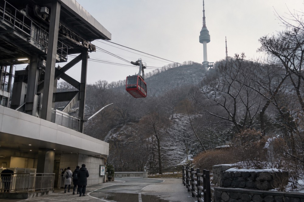 A cable car cabin ascending the steep slope toward N Seoul Tower in winter